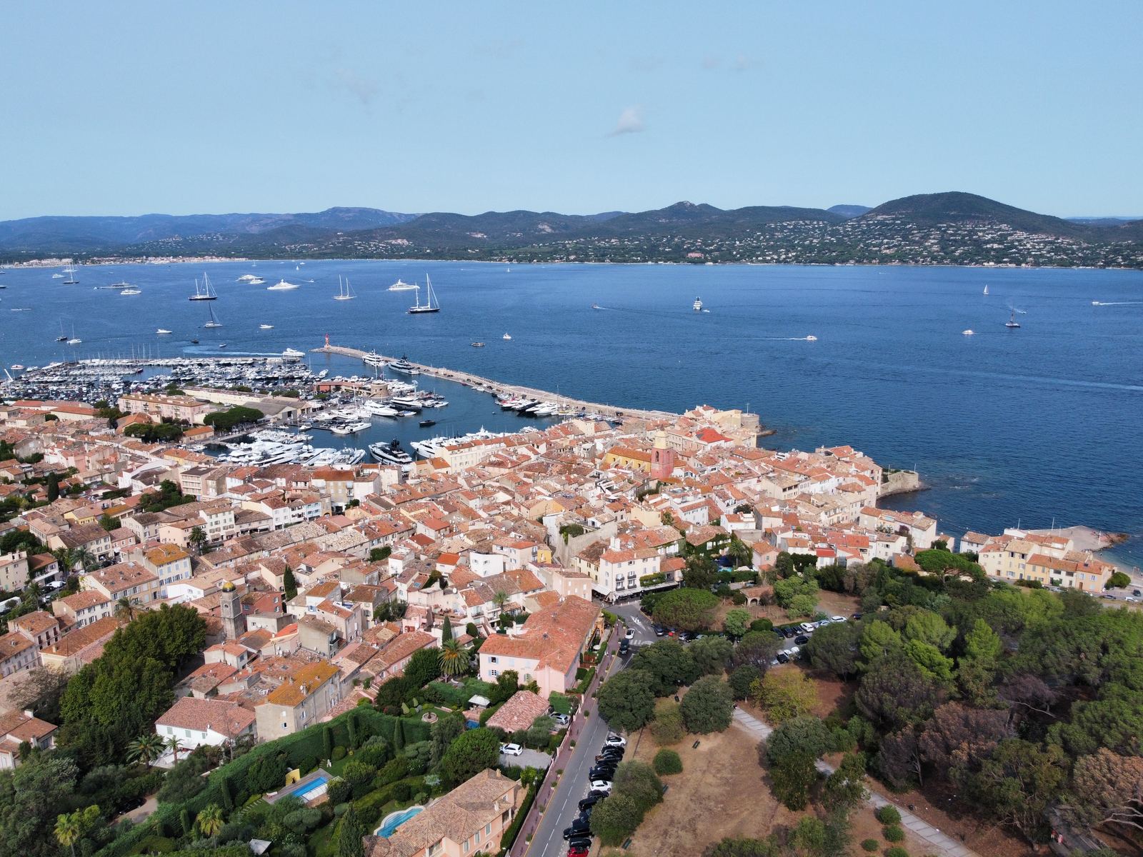 Saint Tropez from above — terracotta rooftops, the old harbour, superyachts, deep blue bay